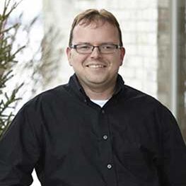 Male dental team member smiling in a professional portrait outside the dental office